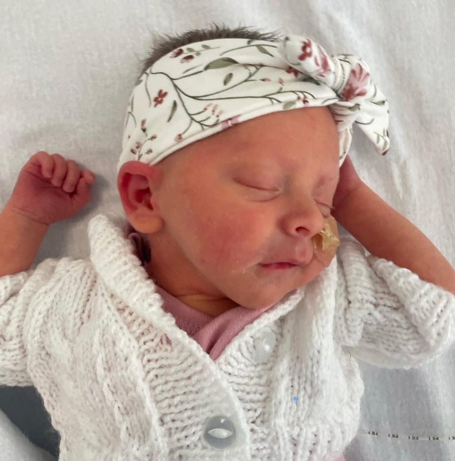 Premature baby girl in headband and cardigan
